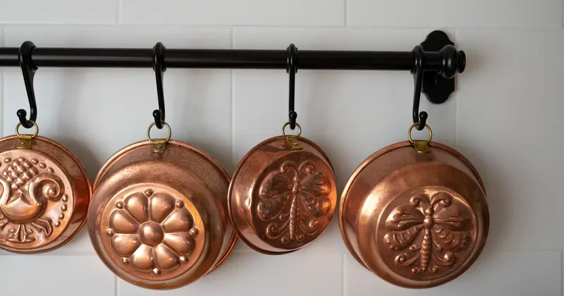 Old-fashioned copper baking pans hanging on a kitchen wall