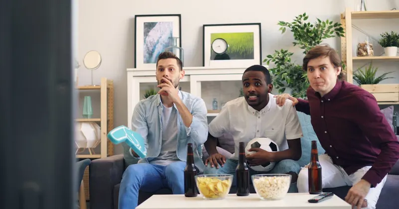 Friends watching a sports game on a couch during game day party