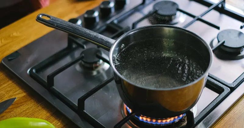 Boiling water in a pot on a kitchen burner with steam rising