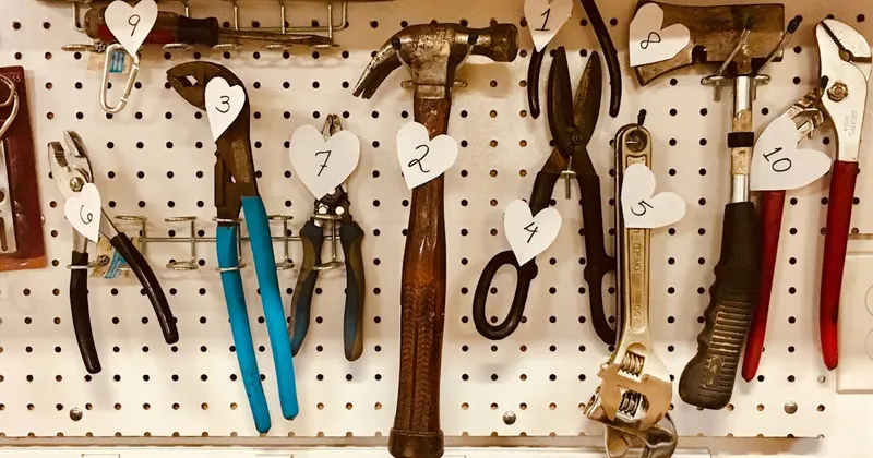 Handheld tools hanging organized on a workbench pegboard