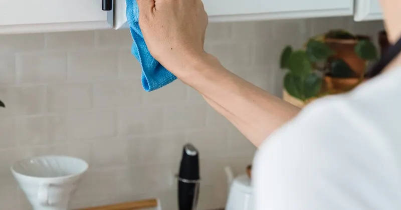 Person cleaning the handle of a cabinet with a cloth